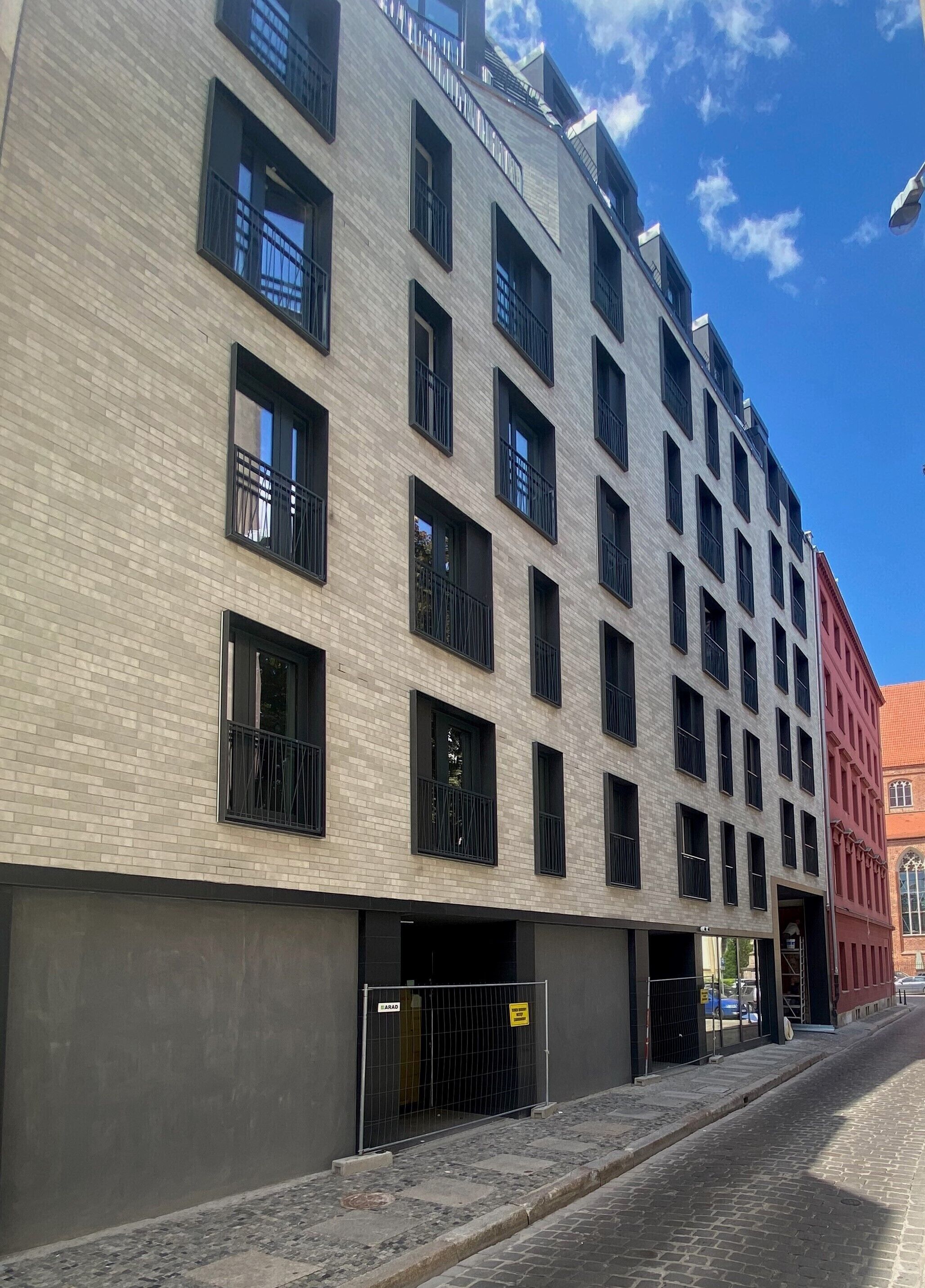 Un edificio de varios pisos con fachada de ladrillo, varios balcones y una entrada con portón.