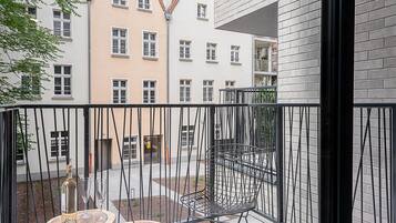 Ein Balkon mit einem Metallstuhl und einem kleinen Tisch, auf dem eine Flasche und Gläser stehen.