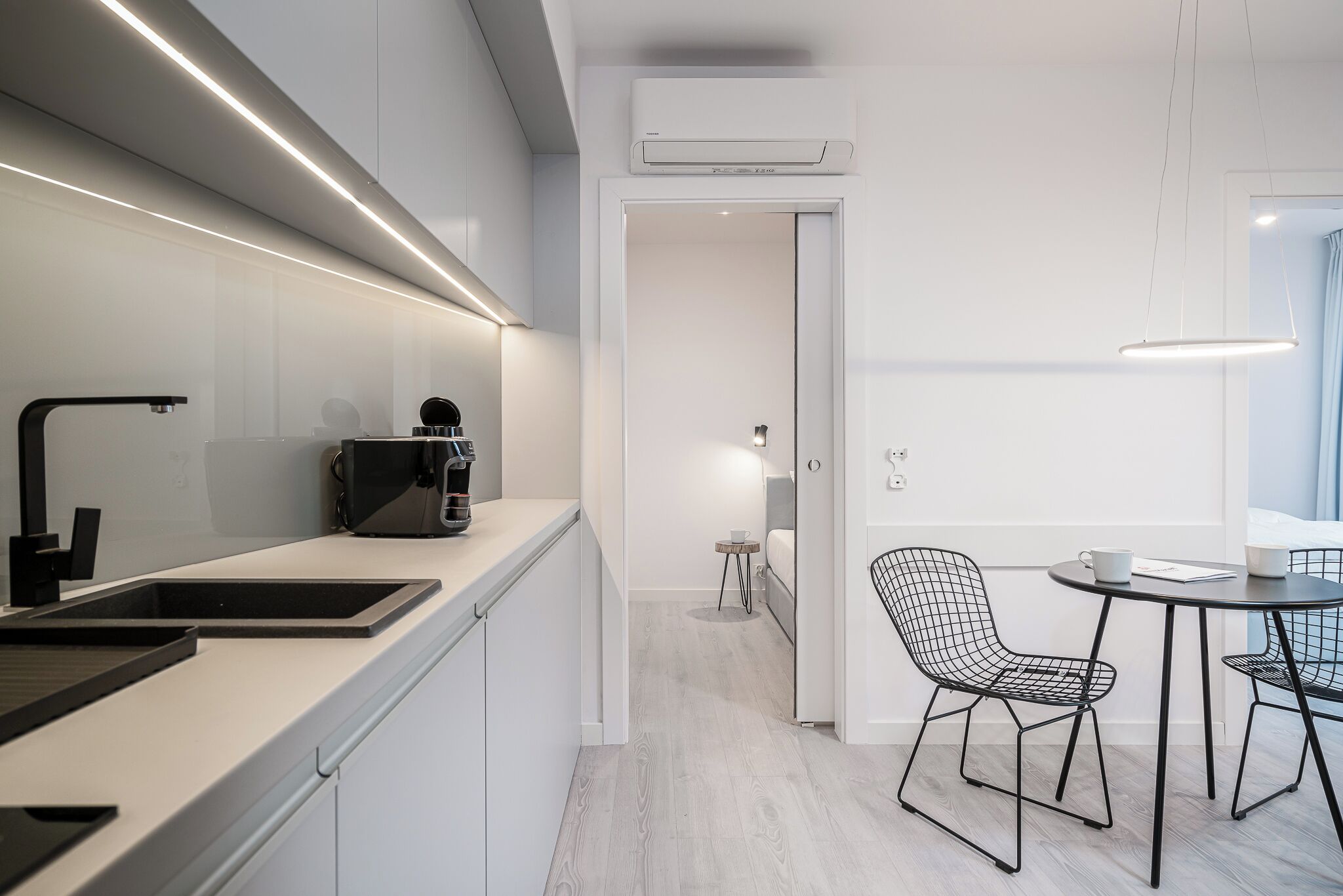 Eine moderne Küche mit Kaffeemaschine, ein Essbereich mit Tisch und Stühlen sowie eine Klimaanlage an der Wand.