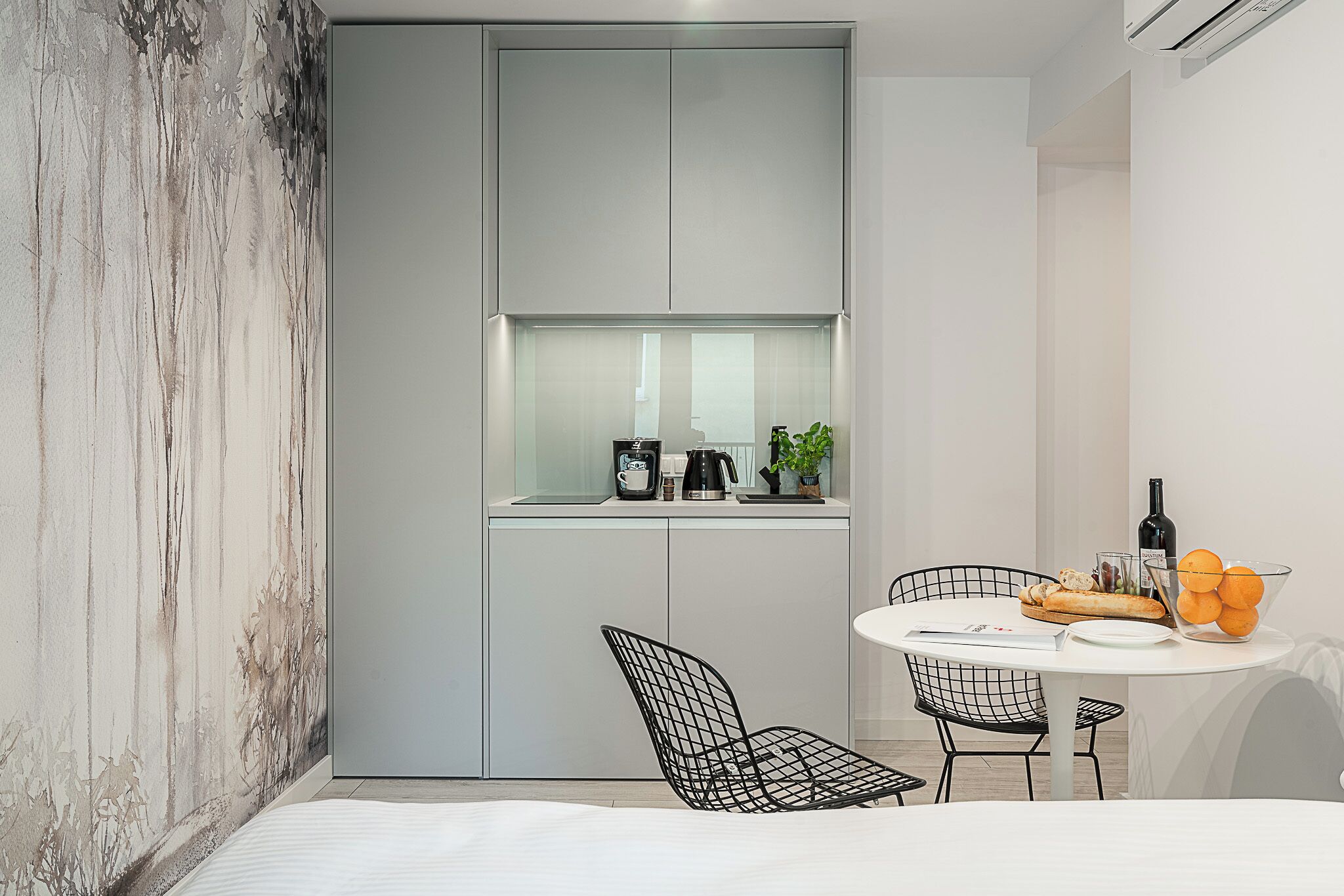 Eine moderne Küche mit integriertem Fenster, ein Essbereich mit rundem Tisch und einem schwarzen Stuhl aus Draht.