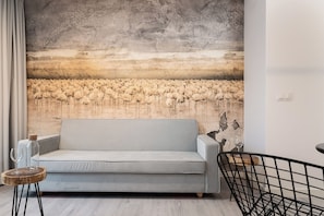 Una sala de estar con un sofá gris, una mesa de centro de madera y un mural con flamencos.
