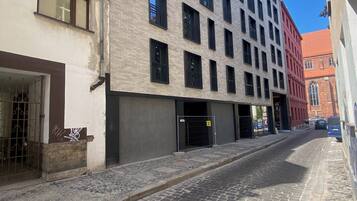 A cobblestone street with a modern building featuring multiple windows and balconies.