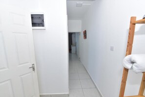A hallway with a white door, a wooden bench, and a small framed picture on the wall. - Soothing 2-bedroom apartment with AC in charming Mont Choisy near Golf&sea (Grand Baie)