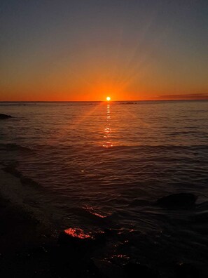 A sunset over a calm sea with waves gently lapping the shore. - Soothing 2-bedroom apartment with AC in charming Mont Choisy near Golf&sea (Grand Baie)