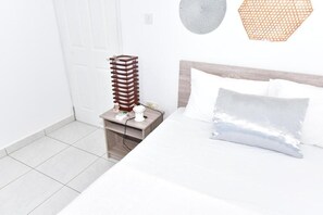 A hotel room with a bed, a nightstand, and a wall-mounted lamp. - Soothing 2-bedroom apartment with AC in charming Mont Choisy near Golf&sea (Grand Baie)