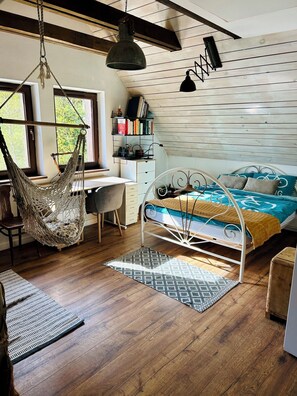 A cozy bedroom with a hammock, a bed with a bicycle-themed bedspread, a desk with books, and a hanging light fixture. - Cheerful cottage on the Red Trail (Pisarzowa, Poland)