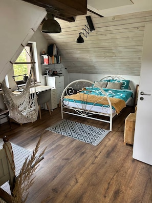 A bedroom with a bed, desk, and hammock.