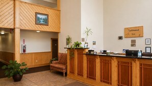 Zona de recepción con mostrador de madera, una silla, una planta en maceta y un letrero que dice 'Tumbleweed Inn'.