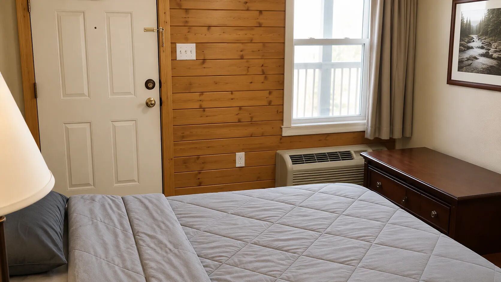 A bedroom with a bed, a dresser, a window with curtains, and a wall-mounted air conditioner.