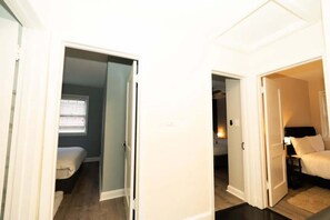 A hallway leading to two bedrooms, each with a bed and a window.