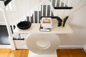 A white staircase with a shelf holding a black bowl, a perfume box, and a gold decorative item.