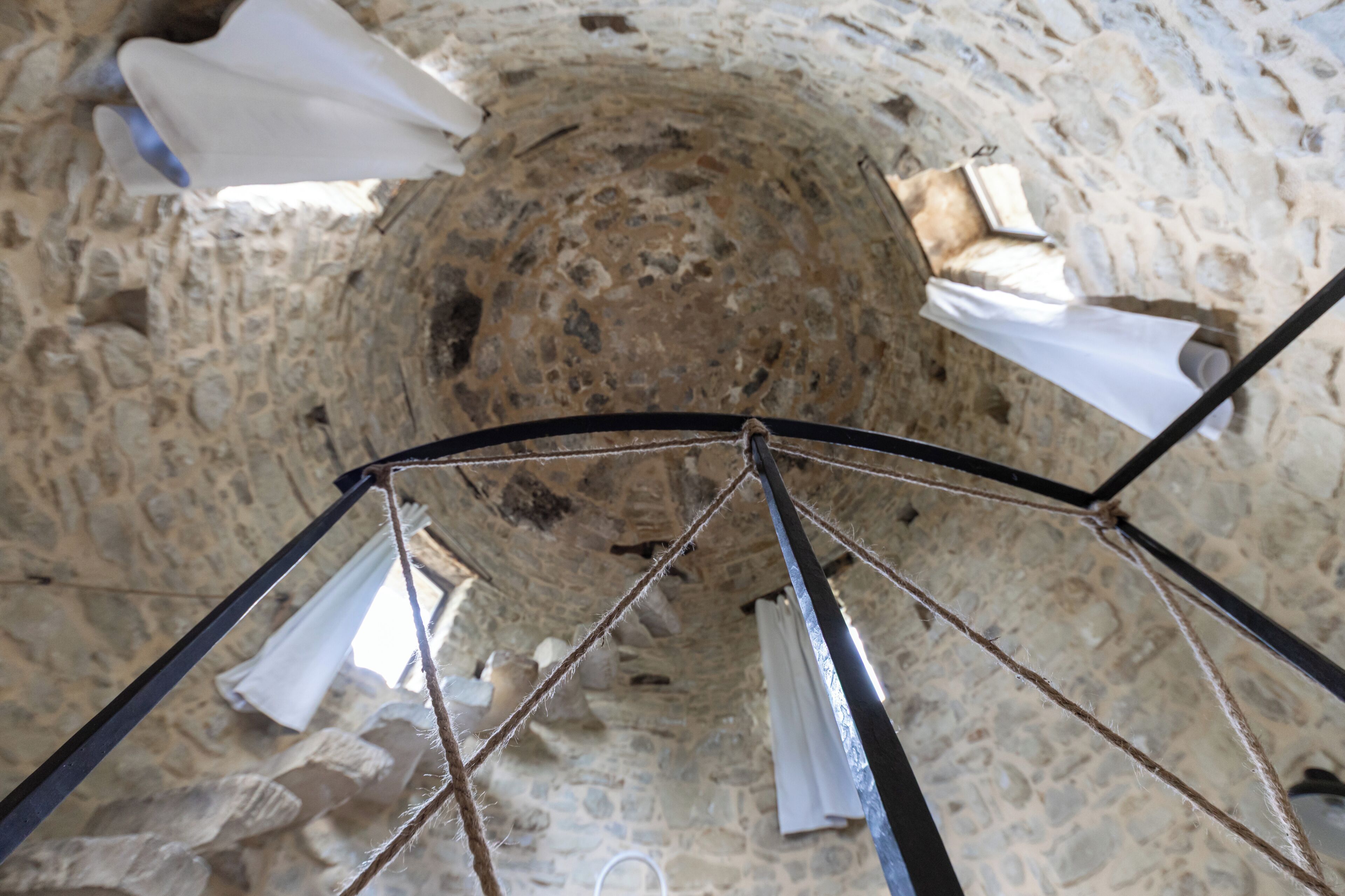 Une structure en pierre, avec une corde et une armature métallique, qui pourrait faire partie d’un bâtiment historique.