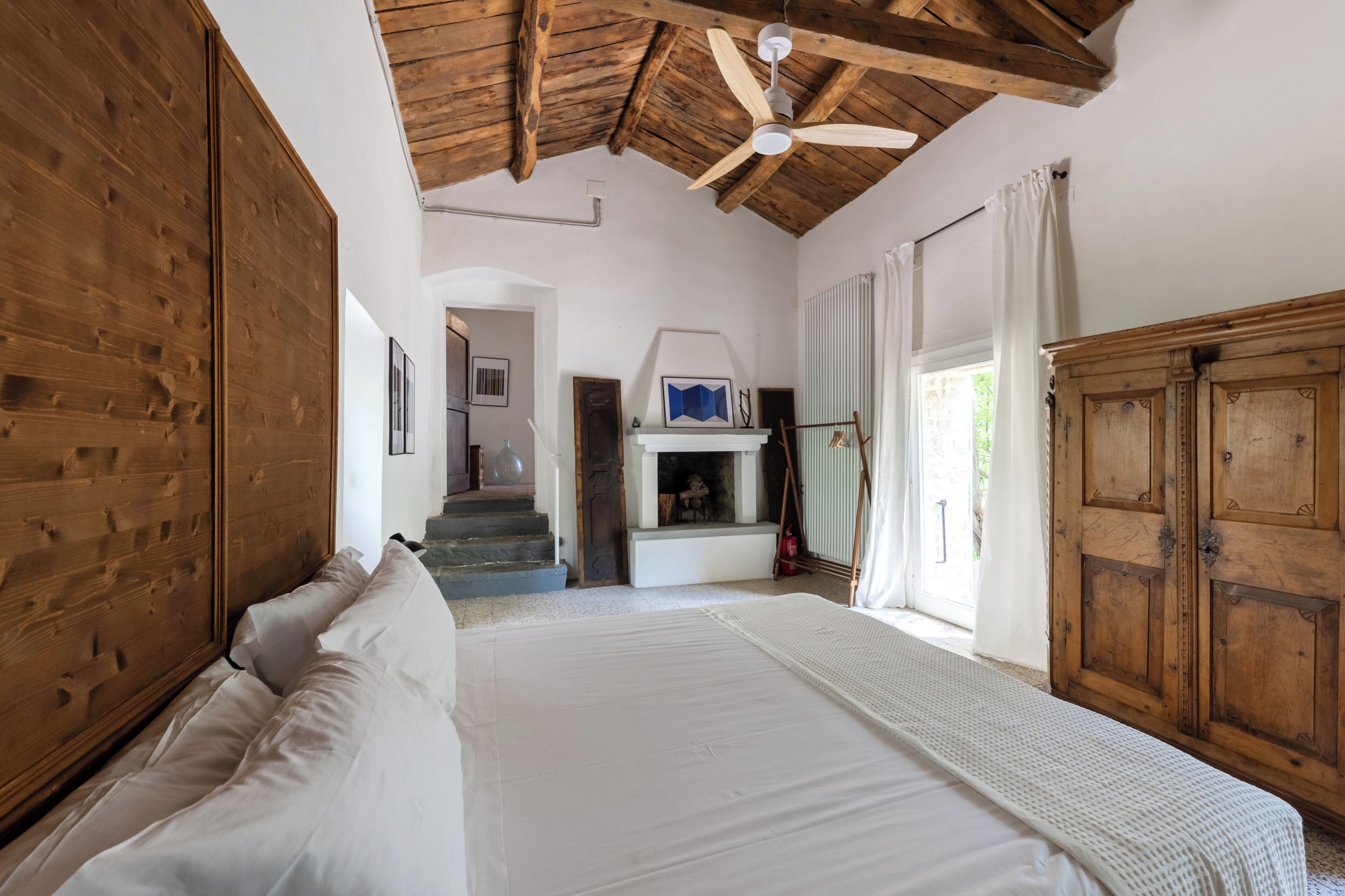 Une chambre à coucher avec un grand lit, une armoire en bois et un ventilateur de plafond.