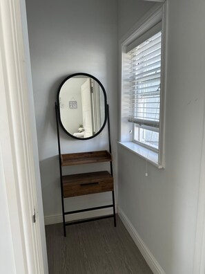 A room with a wooden ladder shelf, a round mirror, and a window with blinds. - Jurassic coast spacious and stylish 2 bed 2 bath apartment. With own parking. (Portland)