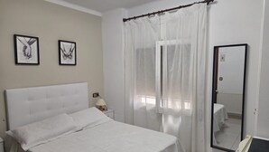 A bedroom with a bed, a nightstand, a lamp, a mirror, and two framed pictures on the wall. - Room 'Habitac. Doble - Cama De Matrimonio' with Shared Pool, Shared Terrace and Wi-Fi (Llançà)