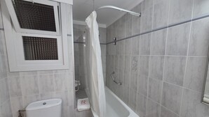 A bathroom with a bathtub, toilet, and shower curtain. - Room 'Habitac. Doble - Cama De Matrimonio' with Shared Pool, Shared Terrace and Wi-Fi (Llançà)