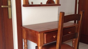 A wooden desk with a chair, a mirror, and a door with a brass handle.