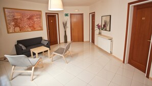 Eine Hotelhalle mit einer Couch, Sesseln, einem Tisch, einem großen gerahmten Bild und einem Spiegel.