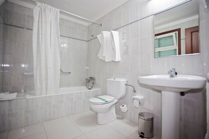 A bathroom with a bathtub, toilet, and sink.