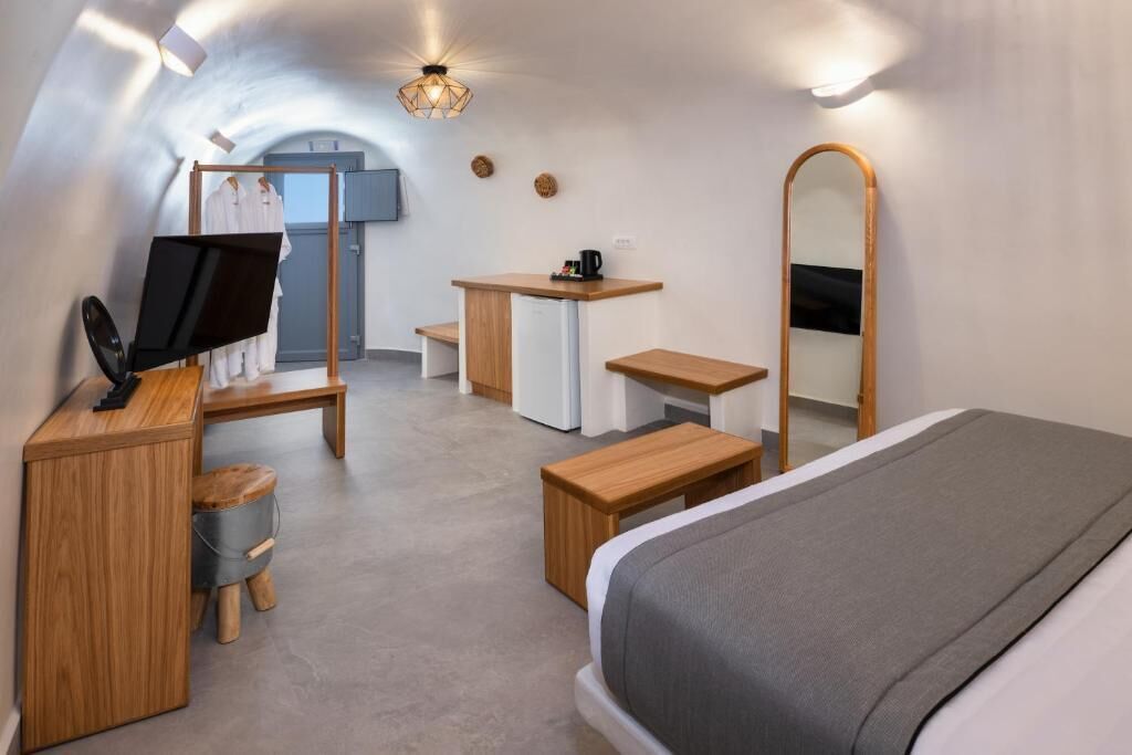 Moderni ja kompakti hotellihuone, jossa on sänky, työpöytä, tuoli, pieni pöytä, peili ja televisio.
