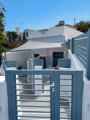 Un edificio moderno con entrada protegida por una reja, un letrero que dice 'CAVORA SUITES' y una escalera que lleva a la entrada.