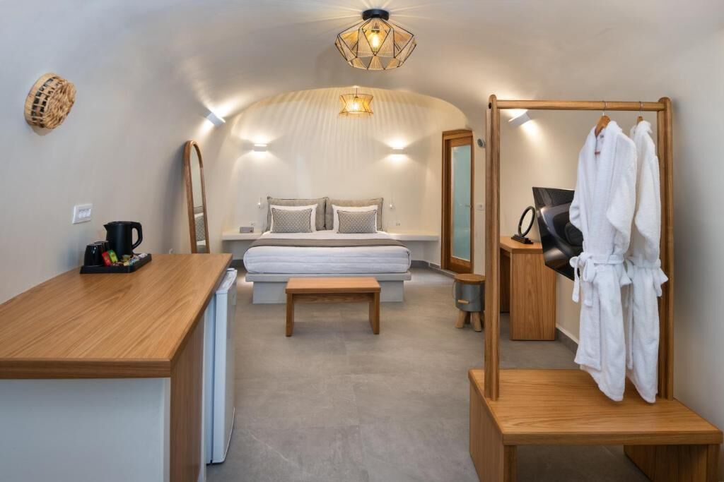 Een kleine slaapkamer met een bed, nachtkastje en een houten bankje.