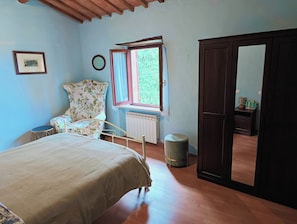 A bedroom with a bed, a chair, a window, a radiator, a door, and a small stool. - Casa al Poggio. An 18th-century farmhouse in Val d'Orcia. Perfect for families (Castiglione d'Orcia)