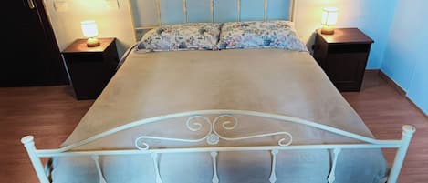 A bed with a metal frame and a floral bedspread, flanked by two bedside tables with lamps.