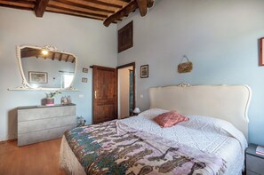 Une chambre à coucher avec un lit, une commode, un miroir et une porte en bois.
