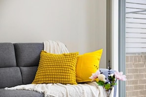 Ein graues Sofa mit zwei gelben Kissen und einer weißen Decke.