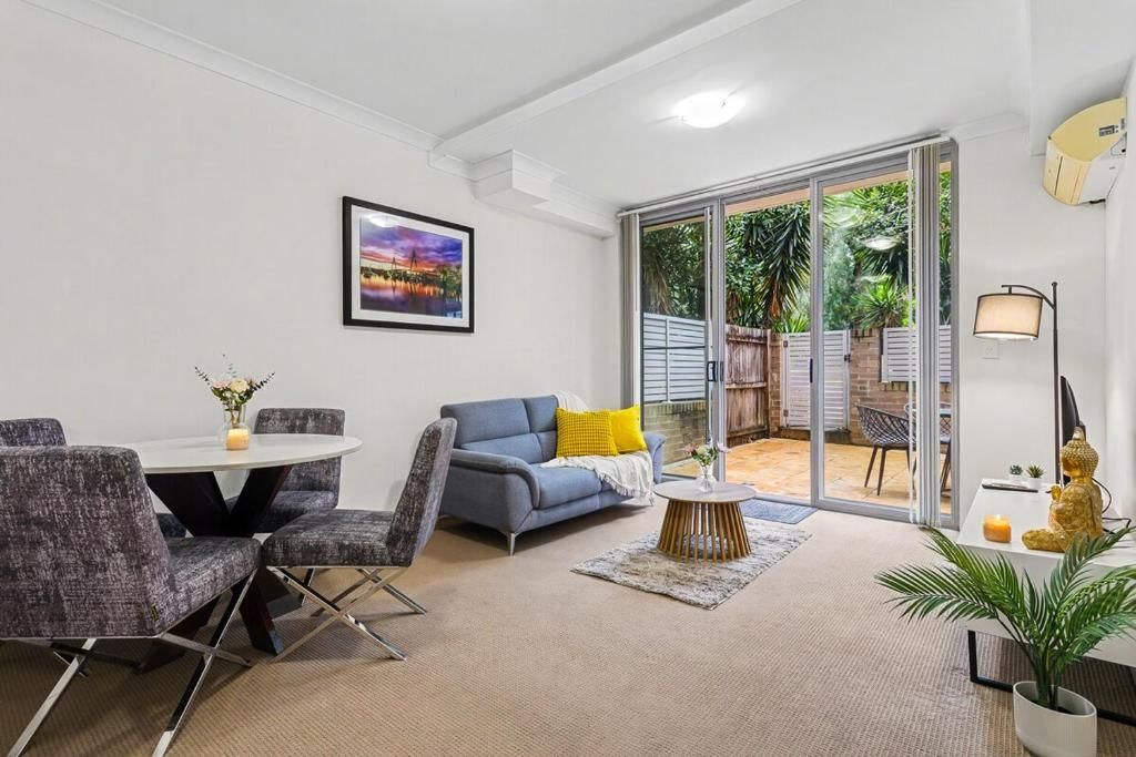 A modern living room with a sofa, chairs, a coffee table, and a dining area.