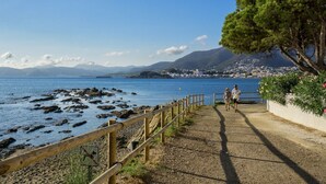 Un passeig marítim amb barana de fusta que condueix a una riba rocosa.