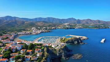Un pueblo costero con un puerto deportivo, casas y montañas al fondo.