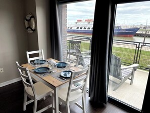 A dining area with a table set for two, overlooking a marina with boats. - Waterfront patio 2 bedroom condo (Sandusky)