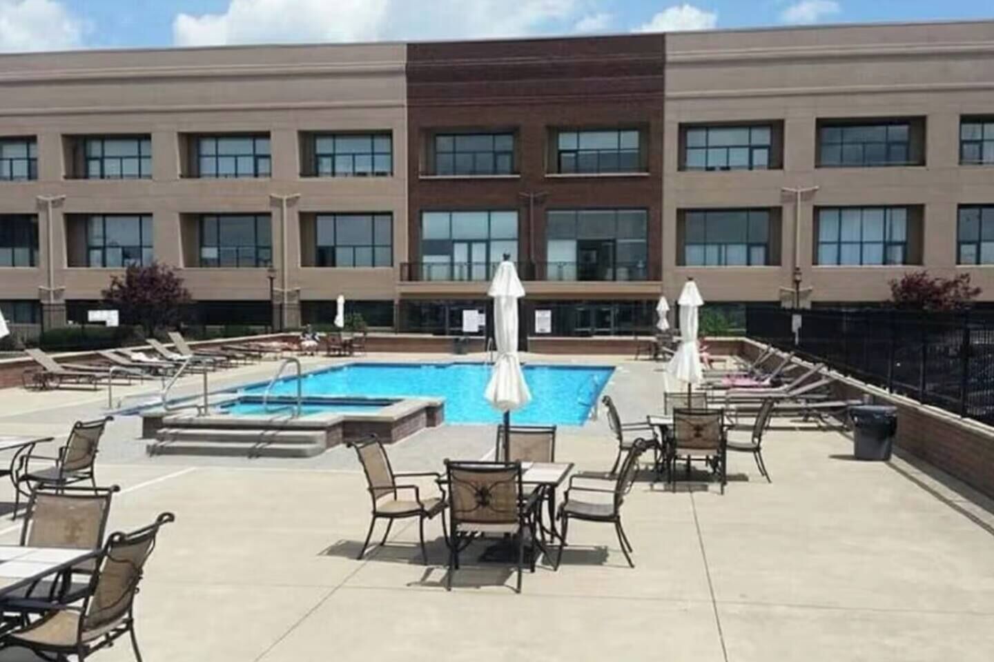 A hotel rooftop with a swimming pool, lounge chairs, and umbrellas.