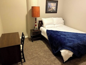 A small, neatly arranged bedroom with a single bed, a nightstand, a table, and a lamp. - Waterfront patio 2 bedroom condo (Sandusky)