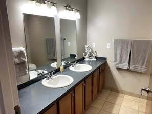A bathroom with two sinks, a large mirror, and a towel rack. - Waterfront patio 2 bedroom condo (Sandusky)