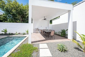 A covered outdoor area with a pool, a dining table with chairs, and a grill. - 3BR Surfside Home with Large Pool & BBQ (Playa Potrero)