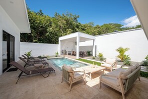 A modern outdoor pool area with lounge chairs, a barbecue, and a covered seating area. - 3BR Surfside Home with Large Pool & BBQ (Playa Potrero)
