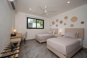 A hotel room with two beds, a desk, a chair, and a window with a view of greenery. - 3BR Surfside Home with Large Pool & BBQ (Playa Potrero)