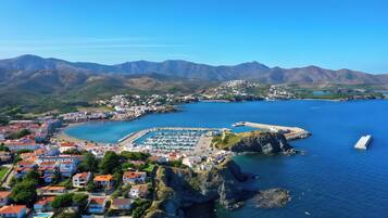Un pueblo costero con un puerto deportivo, casas y montañas al fondo.