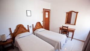 Una stanza con due letti di legno, una scrivania, una sedia, uno specchio e una porta.