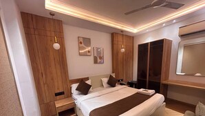 A modern hotel room with a large bed, wooden wardrobe, and a built-in wardrobe with a mirror. - Hotel alvish (New Delhi)