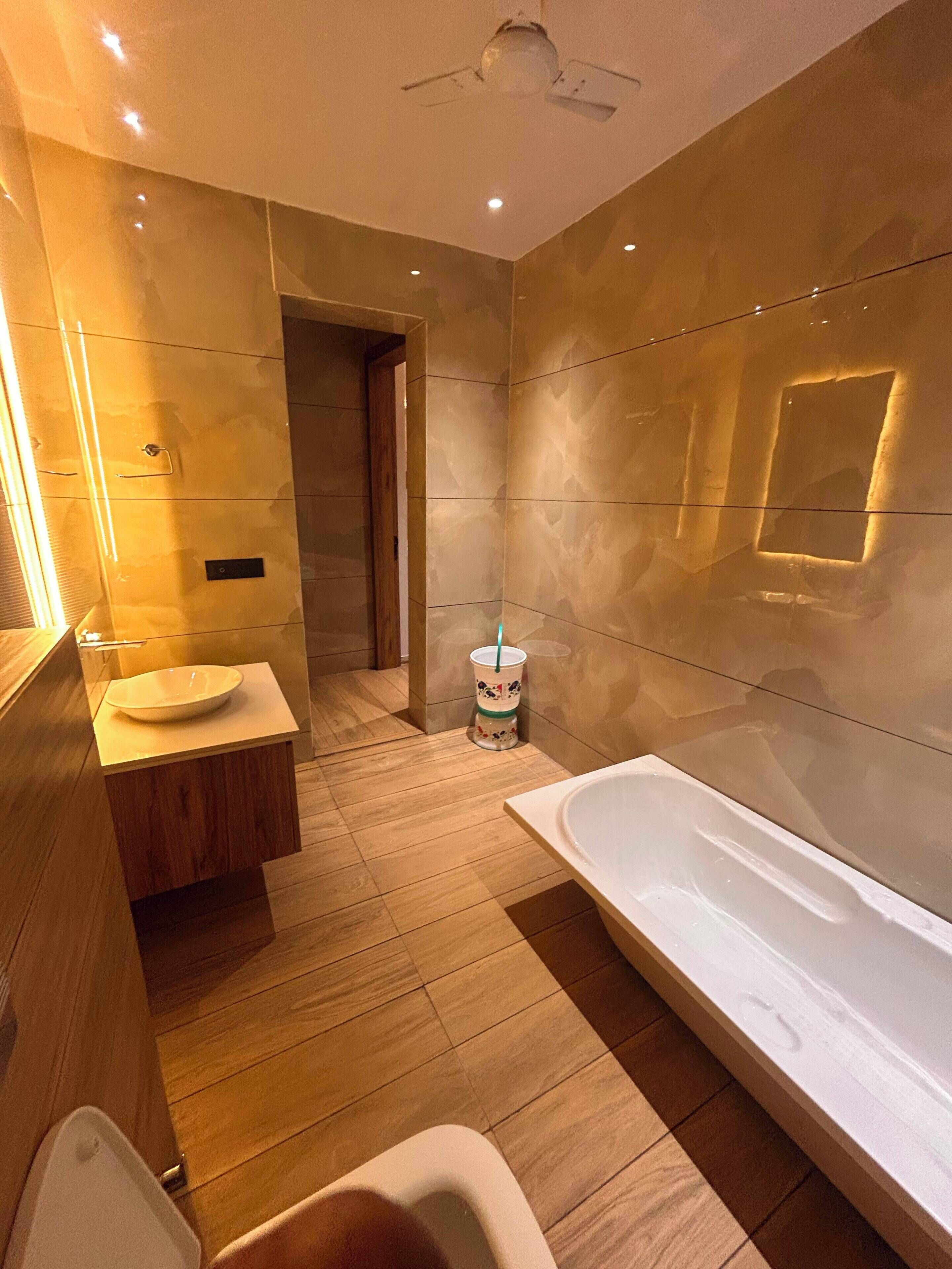 Ein modernes Badezimmer mit einem Holzbadschränken, einer weißen Badewanne und einem gefliesten Boden.