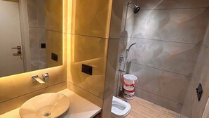 A modern bathroom with a large mirror, a sink, and a shower area. - Hotel alvish (New Delhi)