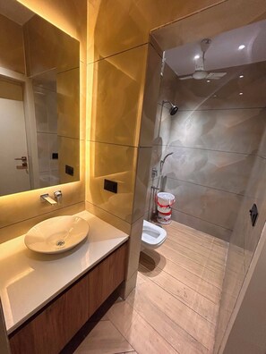 Un baño moderno con un espejo grande, un lavabo y una zona de ducha.