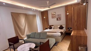 A modern living room with a sofa, a dining table, and a ceiling fan. - Hotel alvish (New Delhi)