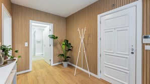 A hallway with wooden paneling, a white door, a coat rack, and a potted plant. - Nomad s Family - 3bdr The Home Base Porto (Porto)