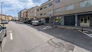 A multi-story parking garage with a blue parking sign, adjacent buildings, and a clear sky. - Nomad s Family - 3bdr The Home Base Porto (Porto)