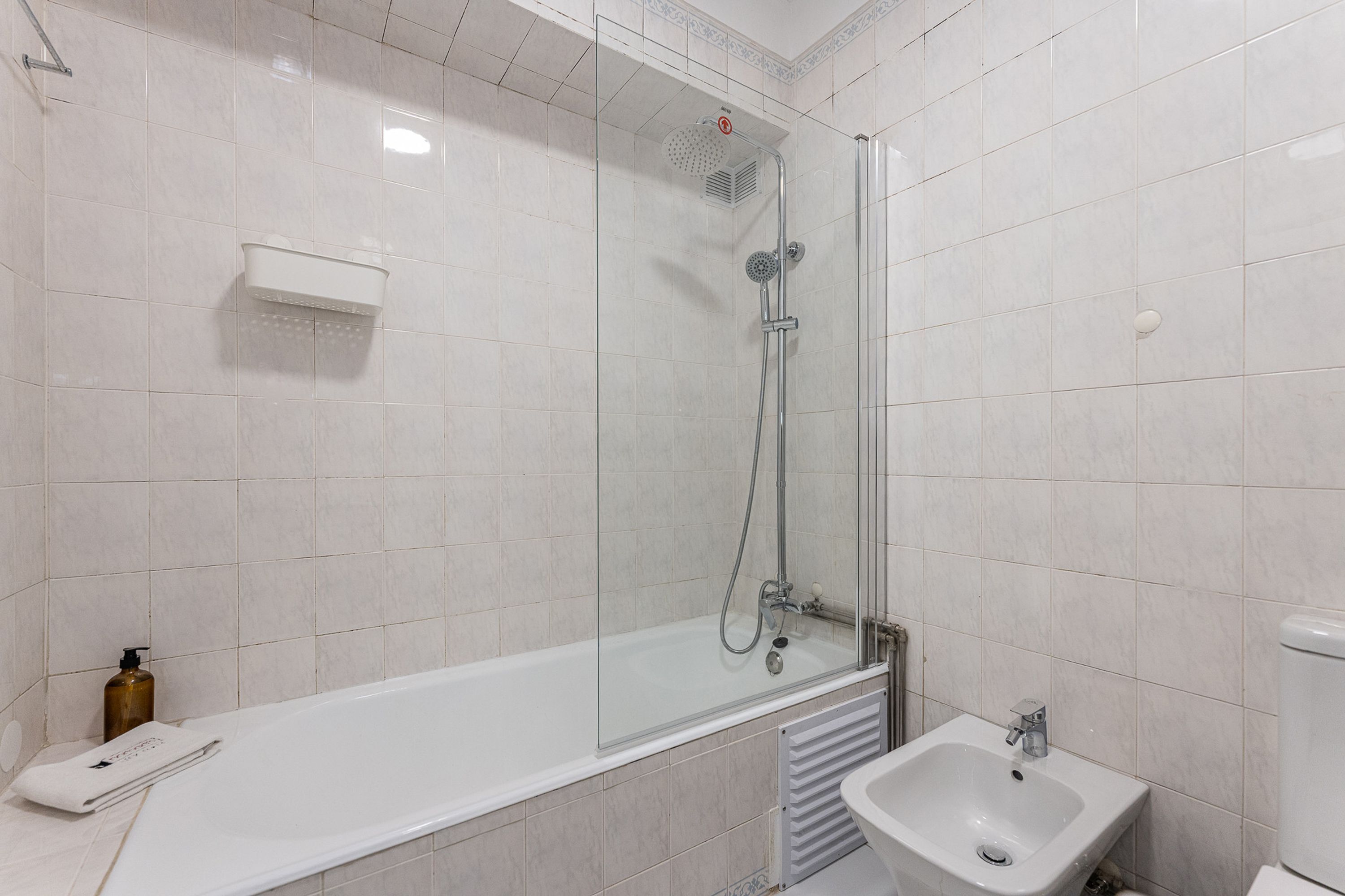 A modern bathroom with a glass-enclosed shower, a white bathtub, and a sink.